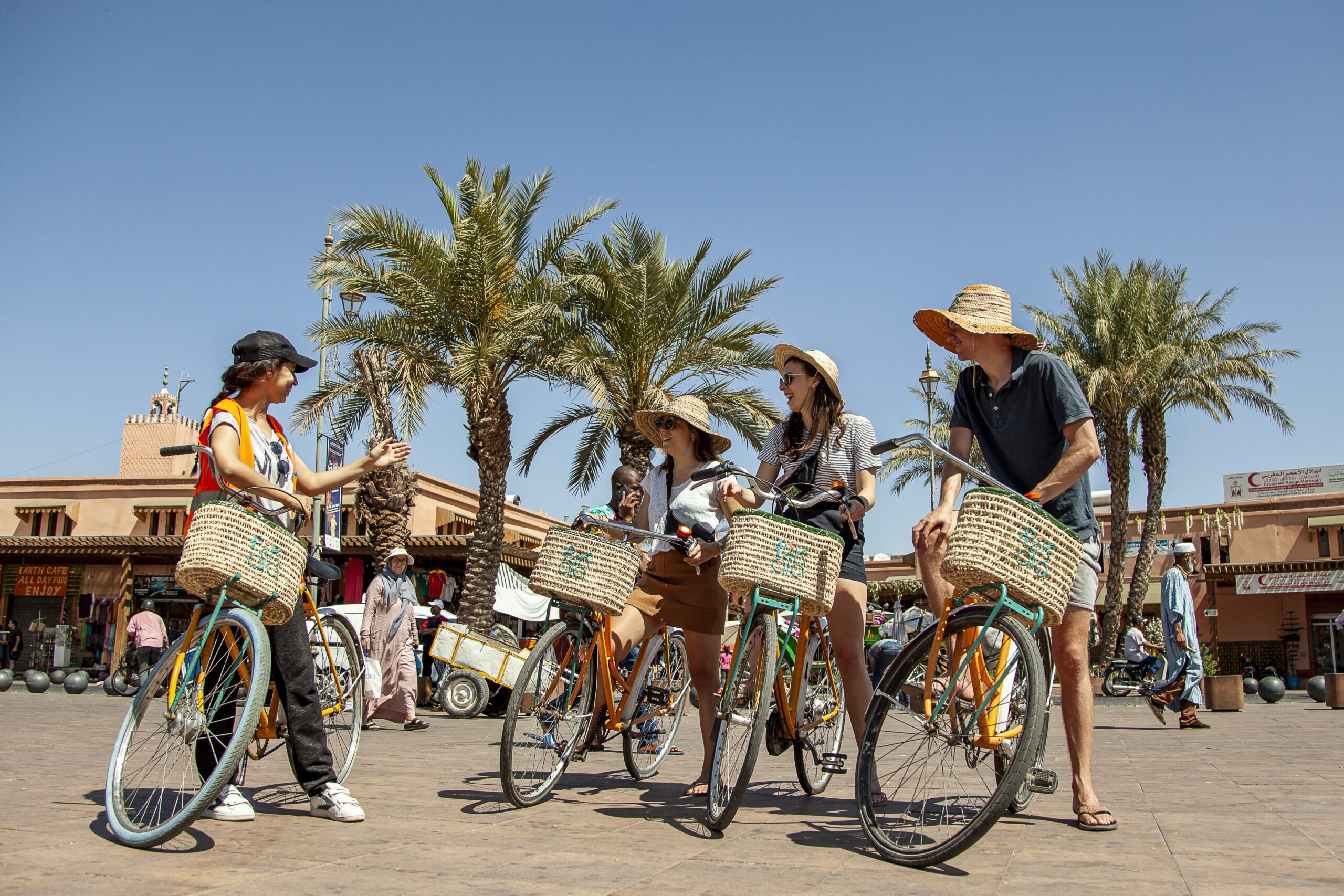 a woman guide on a bicycle with a group of other women riding bicycles in marrakech